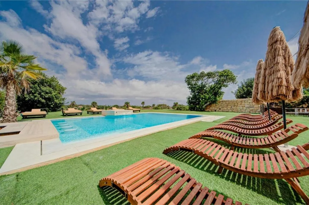 The outdoor pool, limestone deck and loungers on the lawn
