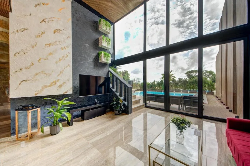 The stone living room from the gallery, looking out to the pool